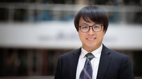 Portrait of Chao Ma in suit smiling.