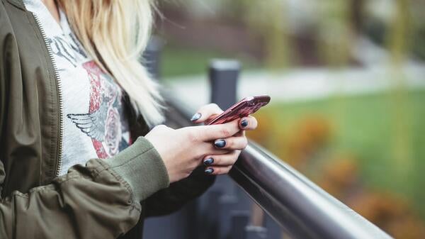 A close-up photo of a young woman holding a cell phone.