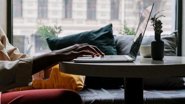 Person working at laptop on table in apartment