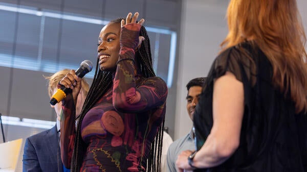 A woman talks into a microphone while smiling