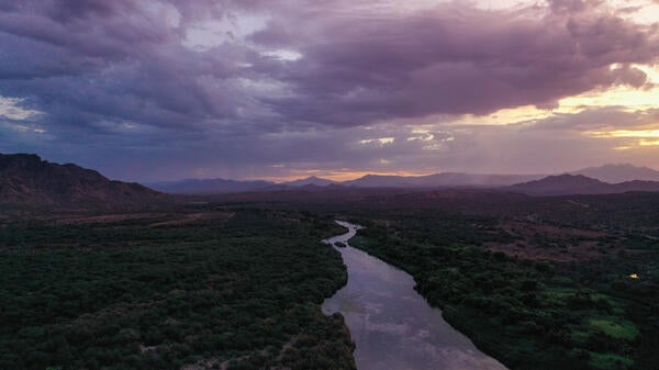 Aerial view of the Salt River weaving its way through a landscape of vegetation surrounded by mountains near Mesa, Arizona.