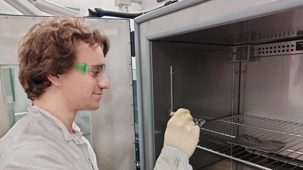 A man wearing safety equipment conducts lab experiments on solar technology.