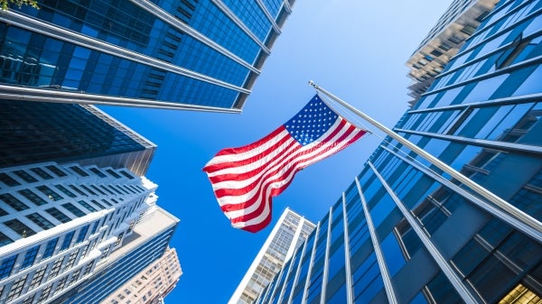 Photo looking up at skyscrapers and an American flag