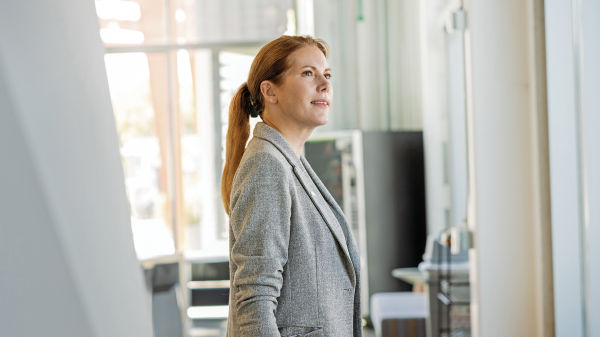 Portrait of a woman with reddish brown hair wearing a gray blazer in an office break room