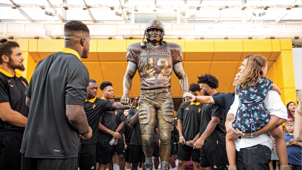 Crowd of football players look at new Pat Tillman statue