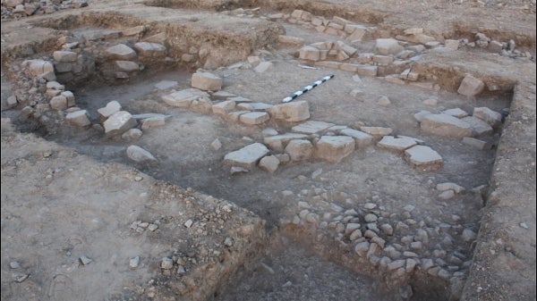 Remains of the structure at al-Khayran, with the cobblestone and flagstone surfaces visible in the foreground and the walls visible in the background.