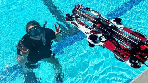 Desert WAVE team member in the water with a robot they used for competition.