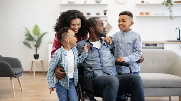 Man using a wheelchair surrounded by his family.