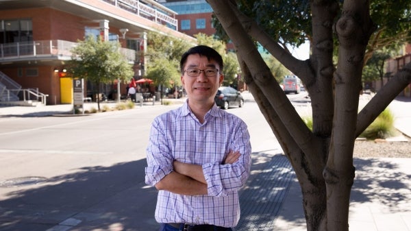 Professor Xuesong Zhou stands along a street featuring multiple modes of transportation. Zhou leads an interdisciplinary team developing open-source systems that help cities build multimodal transportation systems that are equitable and sustainable. Photo by Bobbi Ramirez/ Arizona State University