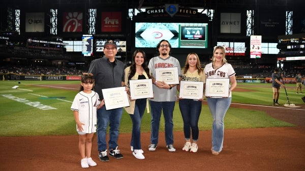 Rafael Martinez standing with a group of five people on a baseball field holding awards.