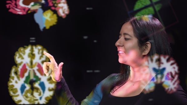 Person reaching out toward a projected image of a human brain.