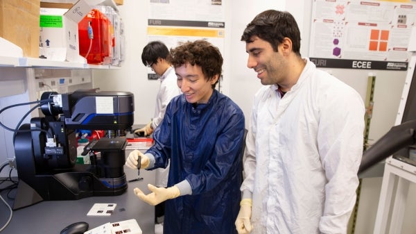 Professor and student wearing lab coats in a lab.