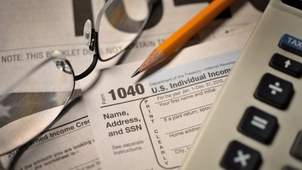 Stock image that shows tax papers, a calculator, glasses and a pencil