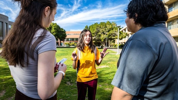 A young woman talks with two people outdoors