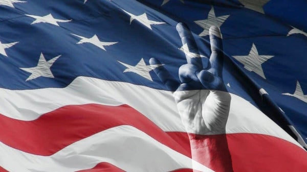 A hand holding up the ASU pitchfork gesture is superimposed on a US flag