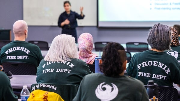 A woman speaks in a classroom full of fire department employees