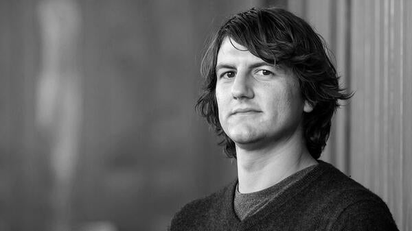 A black-and-white portrait of Director of the Center for Cybersecurity and Trusted Foundations at Arizona State University Adam Doupé.