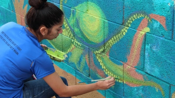 girl in blue shirt paints yellow octopus