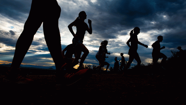 People running are silhouetted against the sunrise