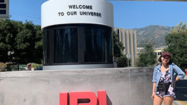 Adrienne stands outside next to the JPL welcome sign.