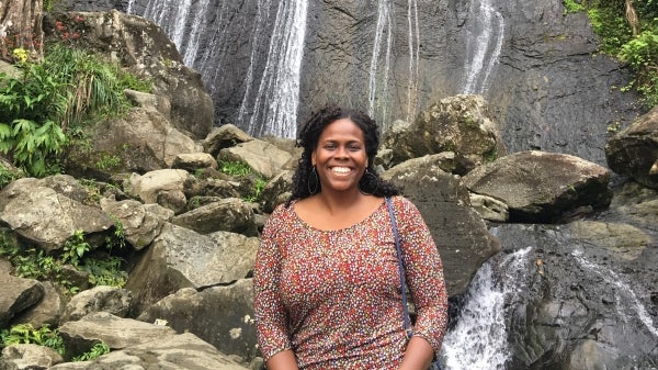 Anaís Deliah Roque smiles while sitting in front of a waterfall