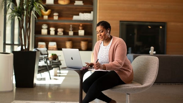 Woman sitting in a lobby using a laptop computer.