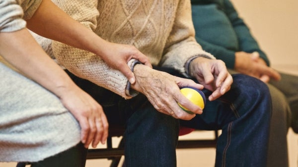 old man holding a ball while a nurse touches his wrist