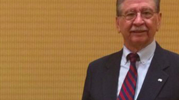 Carlos Vélez-Ibáñez stands in a suit near two of his published books