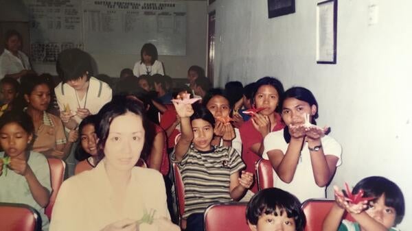 Graduating ASU student Michi Ito, wearing a white shirt, helps children in Indonesia make origami animals. Courtesy photo.