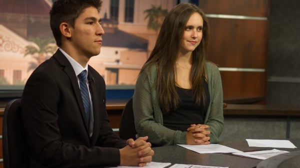 journalism students sitting at a news desk