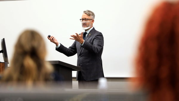 man wearing see through mask speaking to class