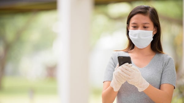 young woman wearing mask and holding a cellphone