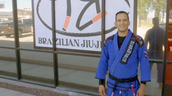 Graduating ASU doctoral student Cristian Lopez Villegas stands outside a martial arts studio. / Photo by Josh Morris.