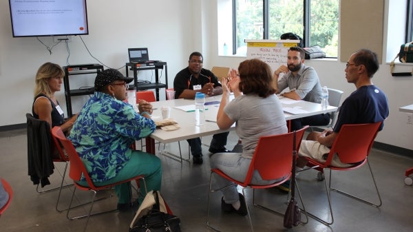 Local community members talk around table about driver-less cars