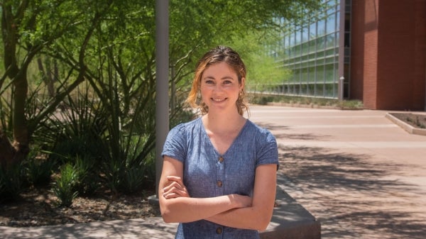 fourth-year clinical psychology graduate student Sarah Curci stands smiling, with arms folded, in front of a tree on ASU's Tempe campus