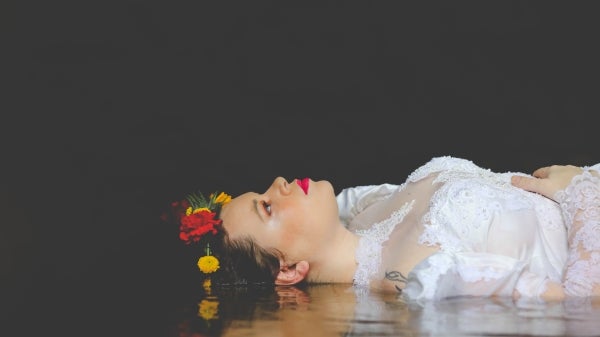 Portrait of Ophelia, lying in the water, with a black background.