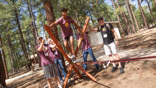 An ASU student prepares to walk across a slack rope as fellow students look on.