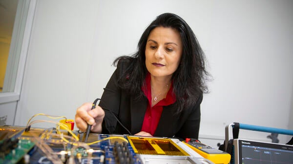 Woman seated at a table working with microelectronics.