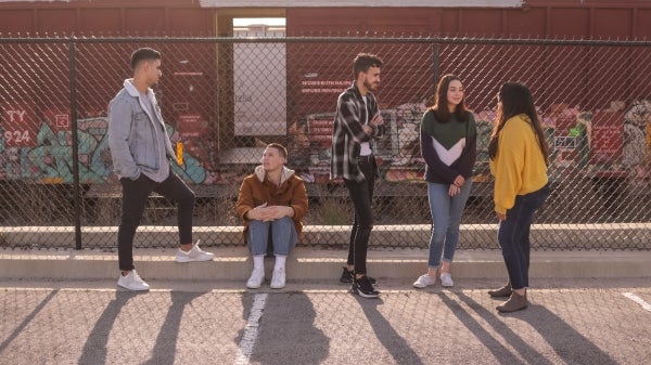 A group of five teenagers talk to each other.