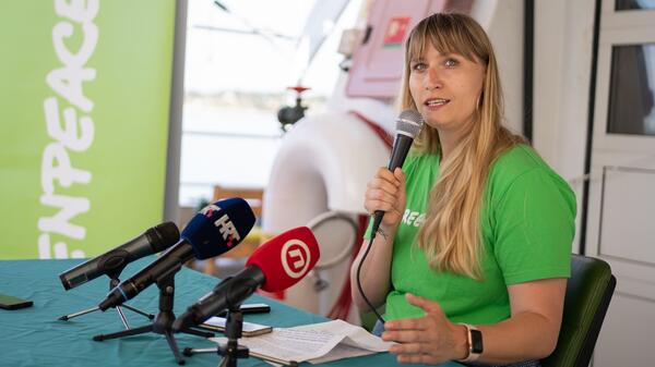 Woman seated at a table speaking into a microphone.