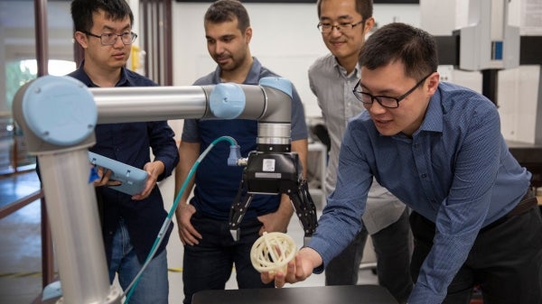 four men using a tool in an automation lab