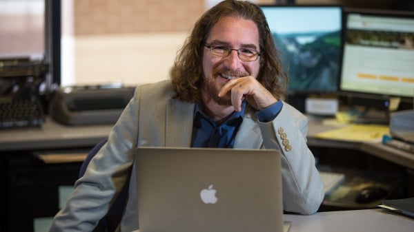 ASU professor Greg Wise sits at a laptop in his office