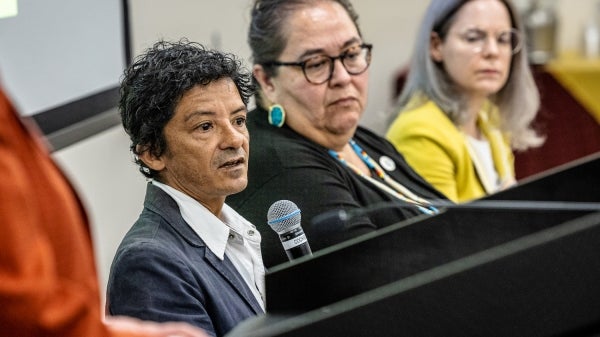 People seated at a table speaking into microphones.