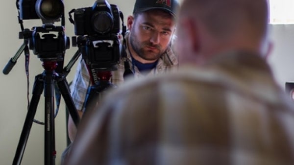 man in background filming man in foreground