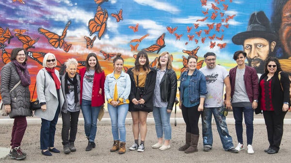 line of people standing in front of mural