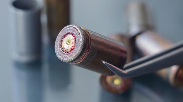 Stock photo of tweezers holding a gun cartridge casing