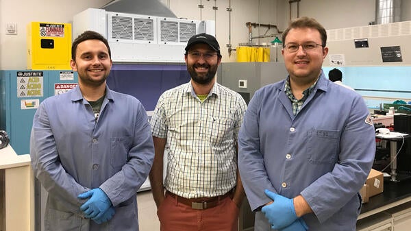 Three people pose in a lab