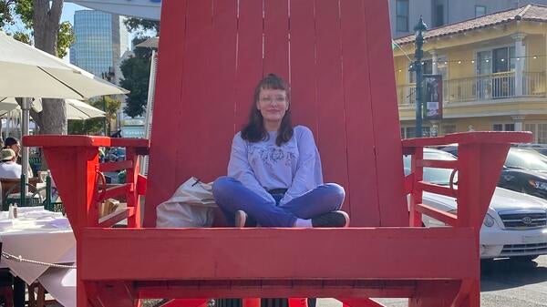 ASU student Genevieve Hook sitting in an oversized, red chair.