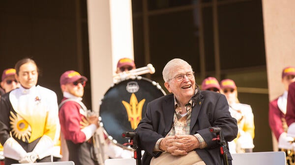 man smiling and sitting in front of marching band at event