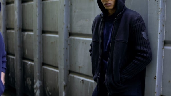 A person in a hoodie standing by a large shipping crate.